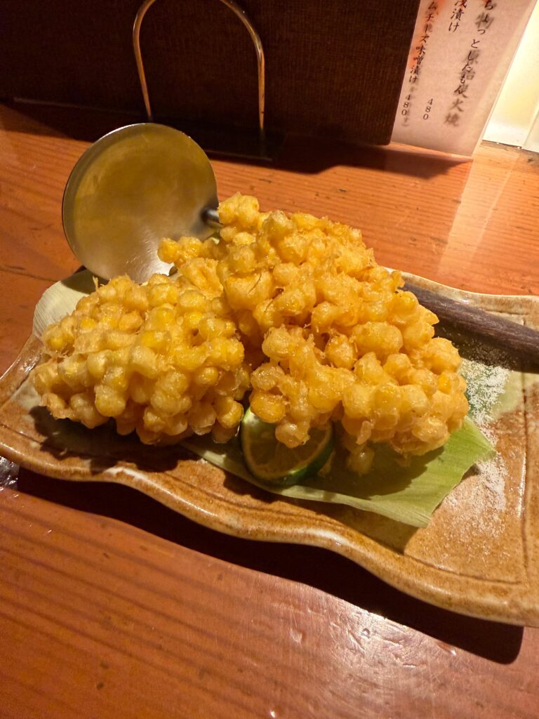 とうもろこしの皮に盛られた、粒がぎっしりのとうもろこしのかき揚げ