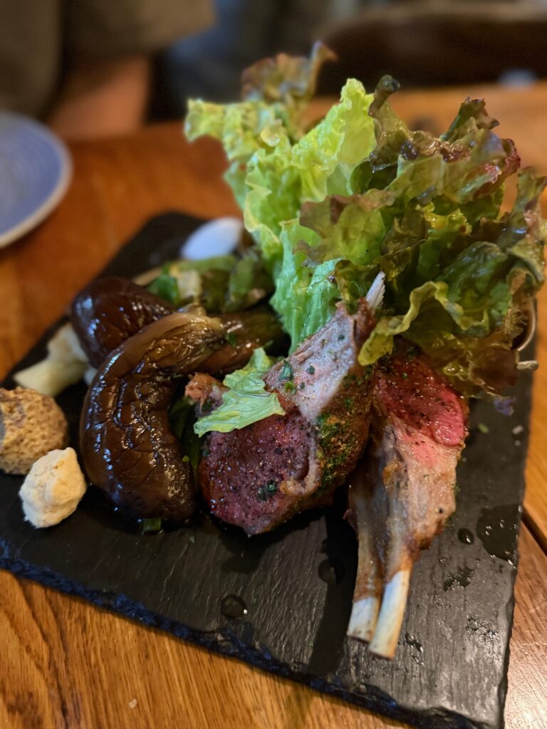 焼き茄子とグリーンリーフを添えた骨付き仔羊のロースト