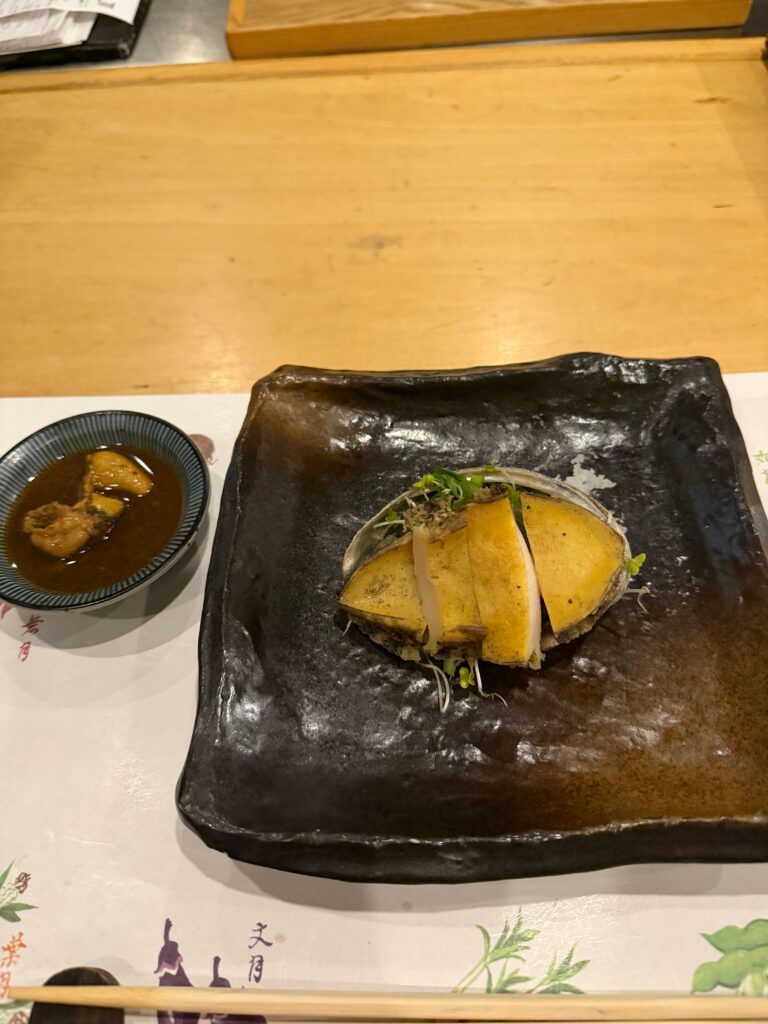 殻に盛られた活あわびの鉄板焼きと肝醤油