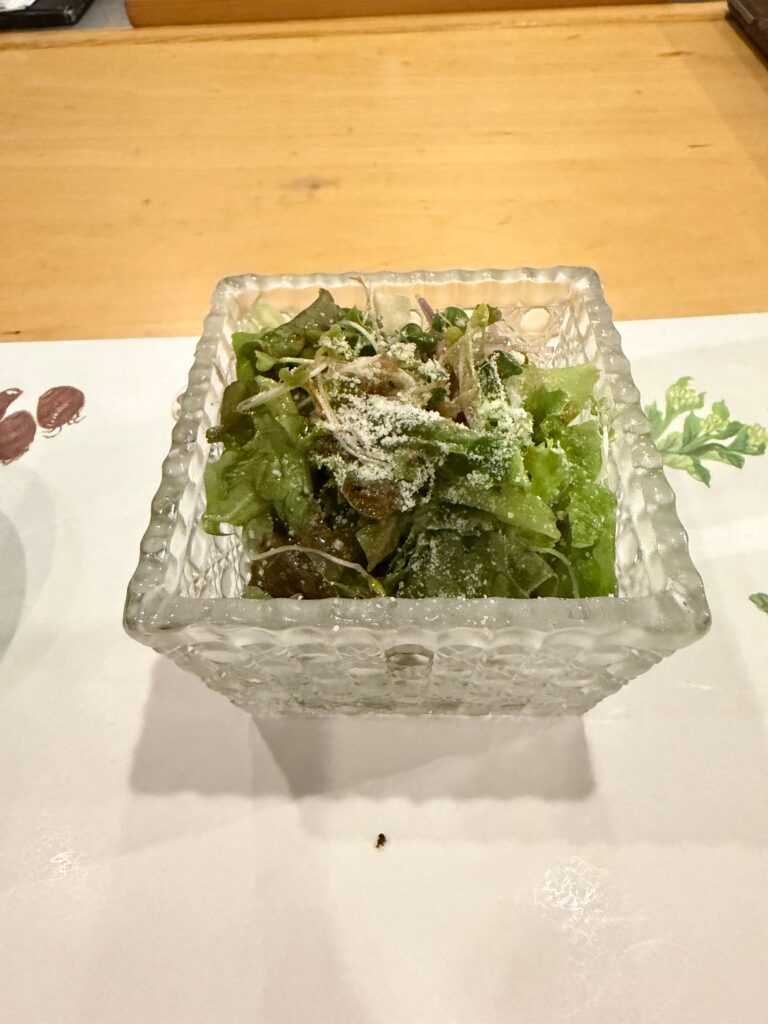 ガラスの器に盛られた、粉チーズをかけたグリーンサラダ